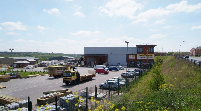 A building material supplier shop with parked cars in a parking lot
