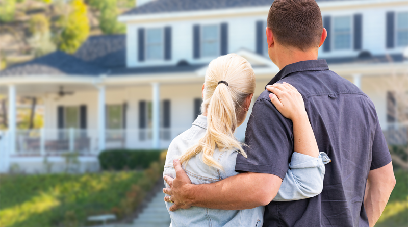 Older couple hugging outside house to support baby boomers housing market article
