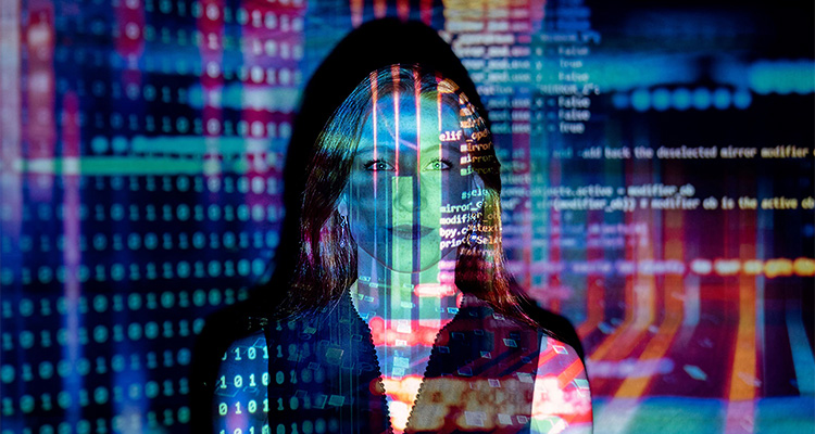 A woman is illuminated by a projection of colorful computer code