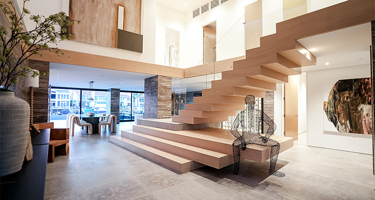 a modern and spacious interior, featuring a prominent, light-colored wooden floating staircase with glass railings