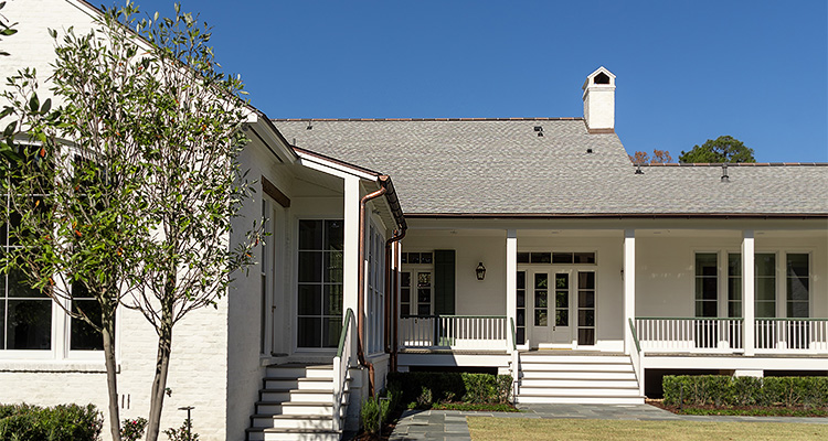 a large, traditional-style house with white painted brick walls and a light grey shingled roof