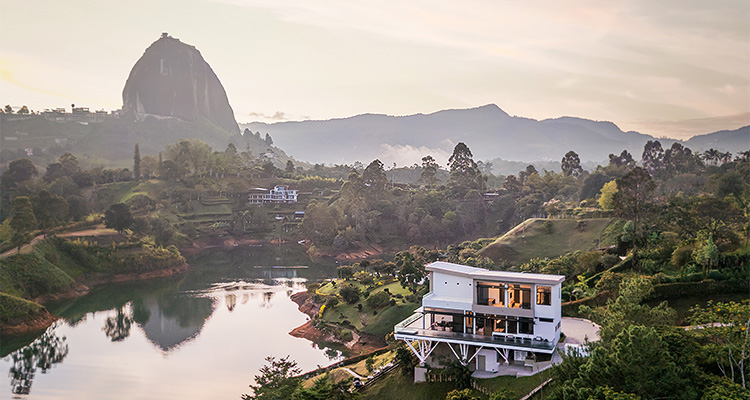 a modern, luxurious house situated on the shore of a lake, likely in Guatapé, Colombia