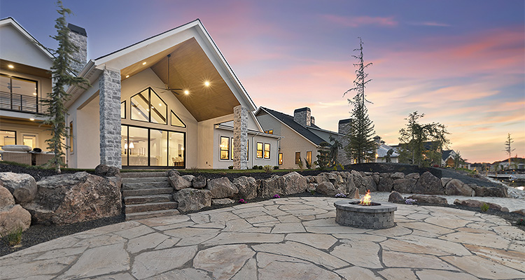s a large, modern house with a stone patio and a fire pit