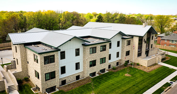 The building has a complex, pitched roof system covered with a light gray or silver-colored metal material.