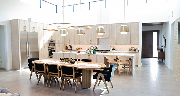 a modern open-plan kitchen and dining area featuring custom wooden cabinetry, a large central island, and contemporary lighting fixtures