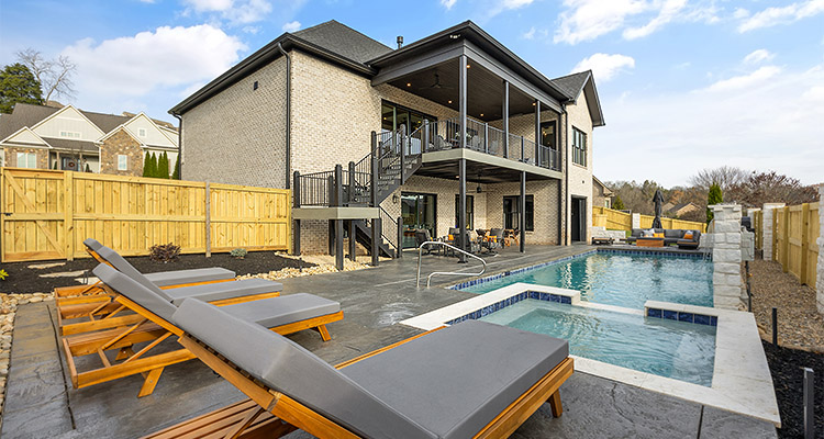he rear exterior of a modern, two-story house, showcasing a well-designed backyard entertainment area