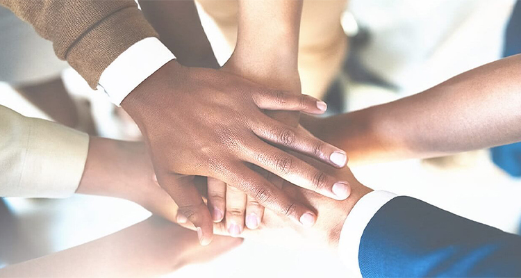 s a close-up photograph of a diverse group of people putting their hands together in a stack