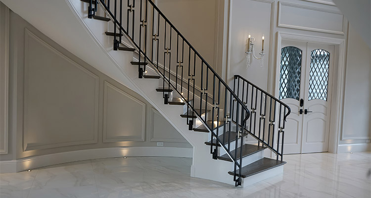 a luxury interior featuring a bespoke curved staircase with a striking black metal balustrade